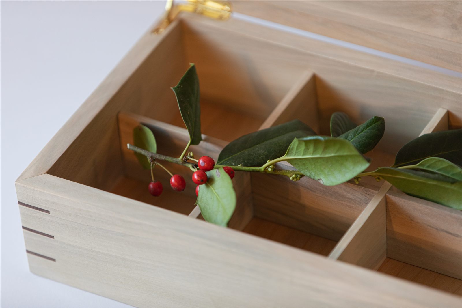 The holly bridal box, open, with a holly sprig and red berries laid across it