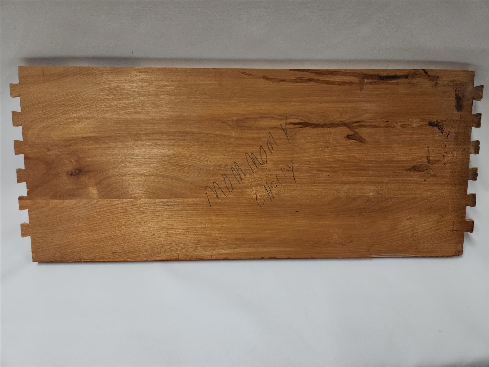 A panel of the dresser with Mom Mom Cherry written on it in pencil