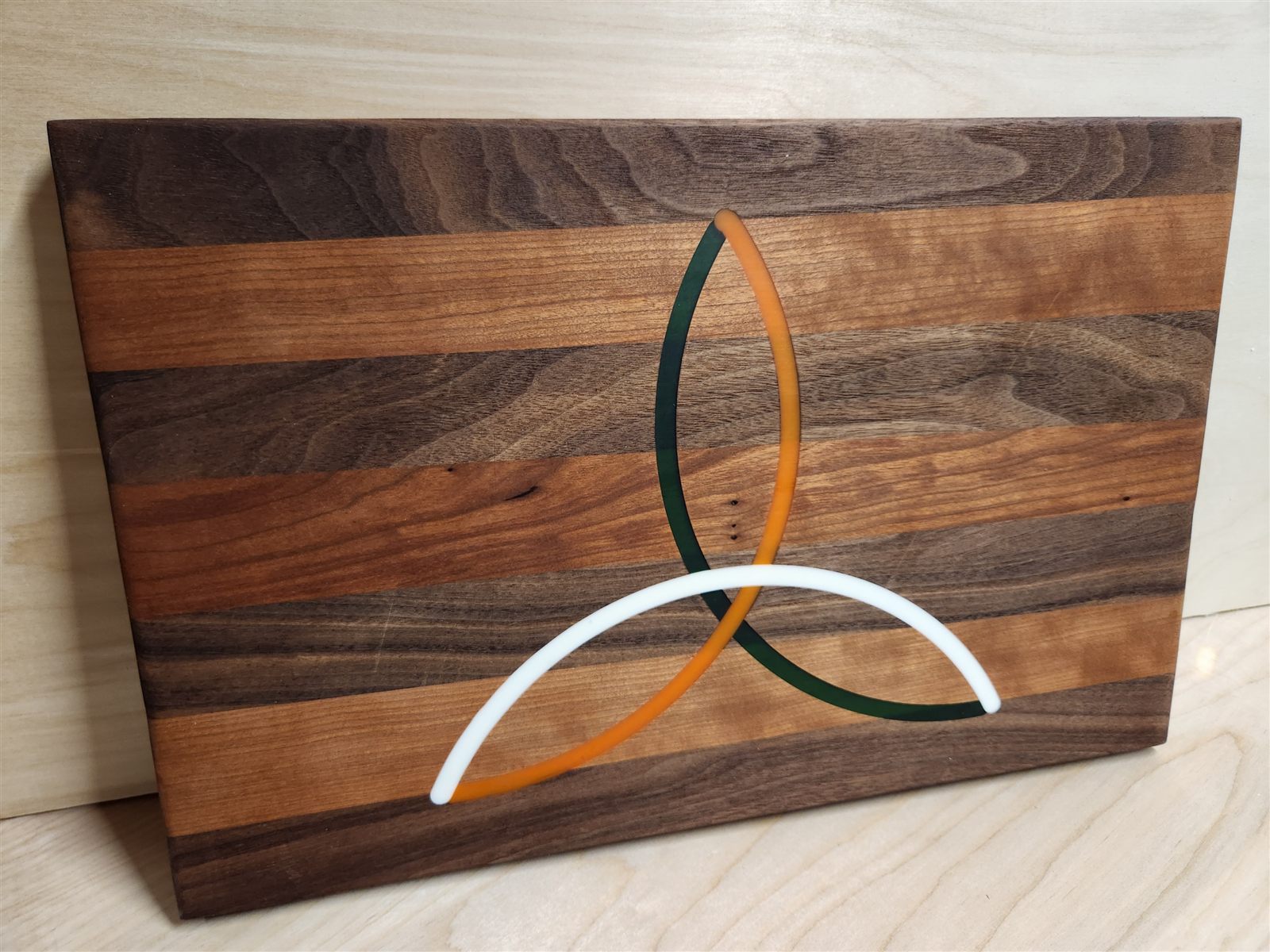 Cutting board with a trinity knot inlaid in colored epoxy