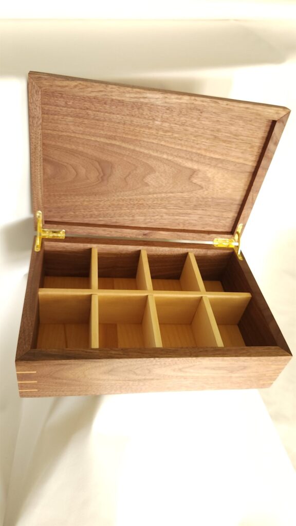 The tea box open, stocked with tea in its cherry compartments